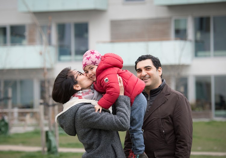 En familie på tre hygger sig foran et nybyggeri. || Soeg-bolig-familie.jpg