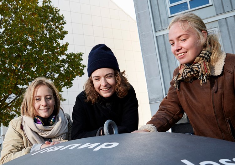 Tre unge kvinder hygger sig foran et byggeri. || Soeg-bolig-ungdom.jpg