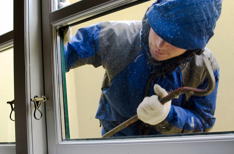En mand i blå jakke forsøger at bryde ind i et hus gennem et vindue. || BM-SIkkerhed-Indbrudstyv.jpg