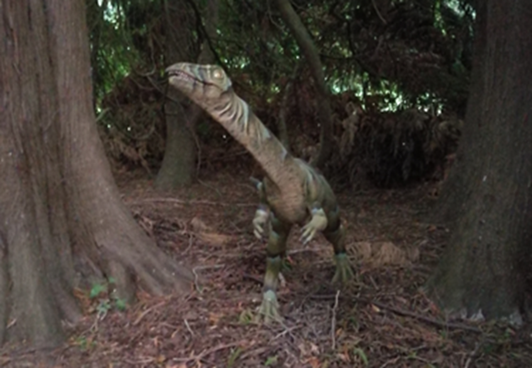 Dinosaur står på en skovbund mellem nogle træer. || Pris_dinosauer_375.png