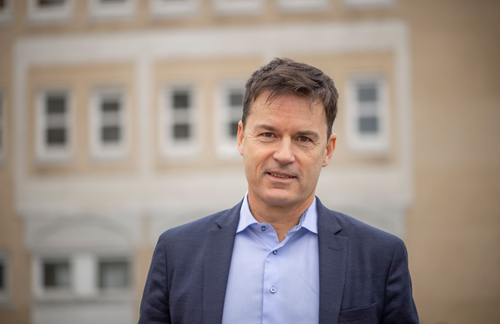 På billedet ses Lars Holmbjerg foran en gul murstensbygning. Foto: Jacob Ljørring