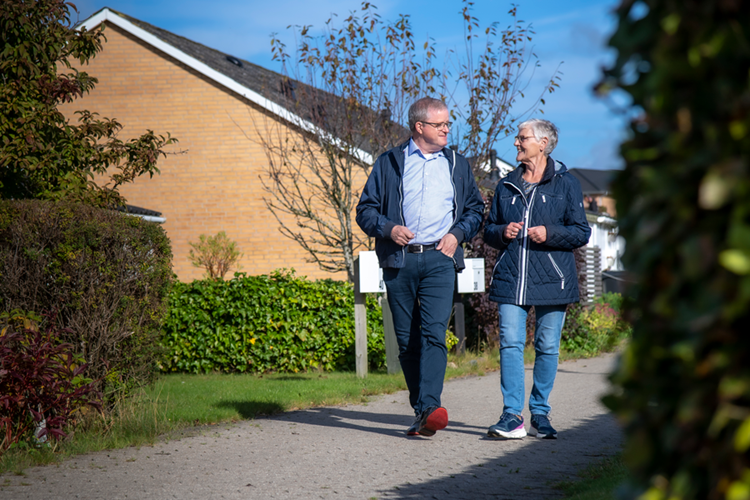 Poul Rasmussen (tv.) og Jonna Tuborg Nielsen ses gående i samtale på en sti mellem nogle huse. Foto: Jacob Ljørring || Sammenlægning Poul&Jonna JL 5778 Web