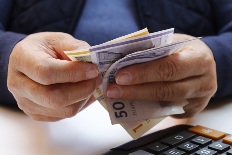 Billede af mandehænder med danske pengesedler mellem fingrene. Nederst til højre i billedet ses dele af en lommeregner. || Indkøbsordning Penge Web