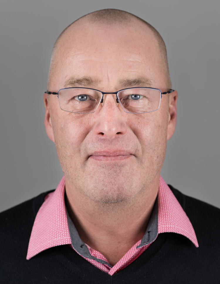 Portrætfoto af Henrik Rafn i lyserød skjorte med sort bluse ud over. || Henrik Ini Web Lille