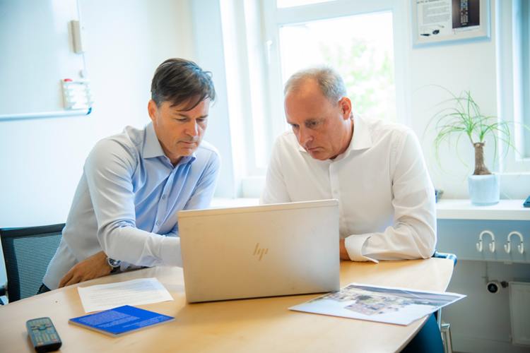 Billede af Lars Holmbjerg (tv) og Thomas Holluf Nielsen, der sidder ved et bord og kigger ind i skærmen på en bærbar computer, som står foran dem. || Thomasoglars 900