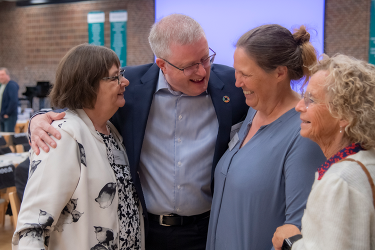Billede af formand Poul Rasmussen, der står og taler med tre kvinder. || Generalforsamling 900