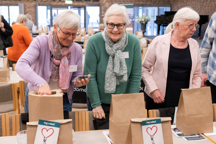 Tre kvinder står ved et bord og kigger i deres goodiebags. || 2023Landskonf JL 9581 900