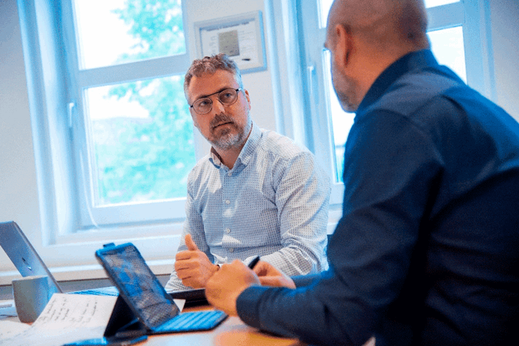 To mænd sidder med deres bærbare computere ved et mødebord. || Nye Samarbejsaftaler Pix Web
