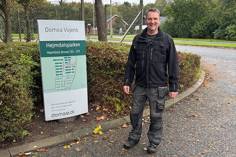 Mand i arbejdstøj står ved skilt, hvor der står Domea Vojens || Keldskov Domea Vojens Web 900X600