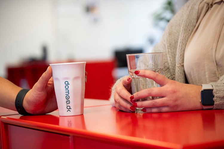 Medarbejdere sidder og taler sammen over en kop kaffe. || Domea Organisation 900X600