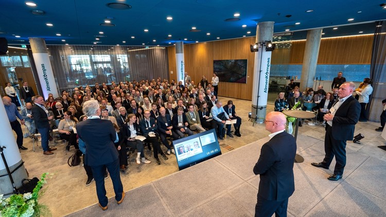 Tre mænd på scenen for et publikum på ca. 200 mennesker i stor sal. || Almenkompas Overdragelse 2 LGM 1600X900