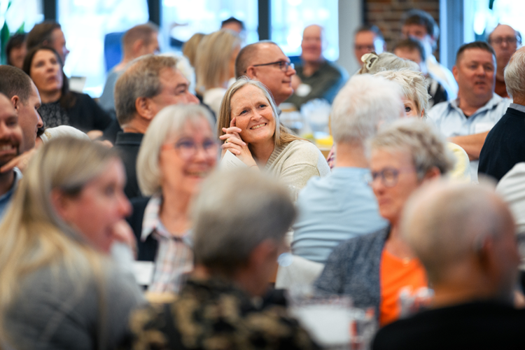 En sal fuld af mennesker med en smilende kvinde i centrum || Domea 260424 134142 LO1